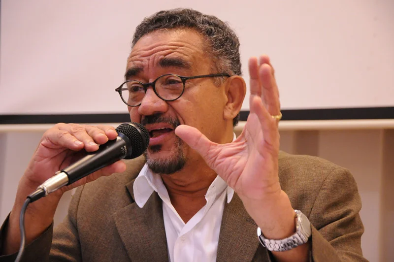 Muniz Sodré falando com um microfone na mão direita e gesticulando com a mão esquerda